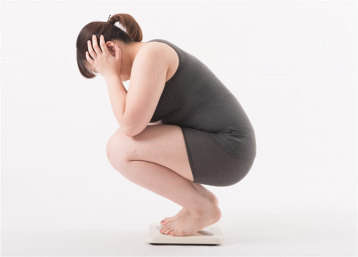 体重計に乗って悩む女性